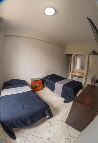 a room with two beds with blue sheets on them at Regency Plaza Hotel in Pisco
