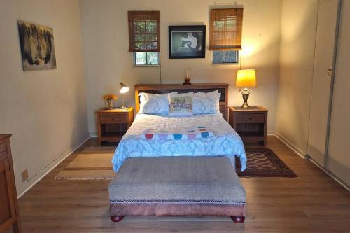 une chambre avec un grand lit et deux tables de nuit dans l'établissement Eagle Owl Cottage, à Gqeberha