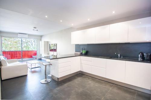 une cuisine avec des armoires blanches et un salon dans l'établissement Beau 3P proche hippodrome - Parking privé, à Cagnes-sur-Mer