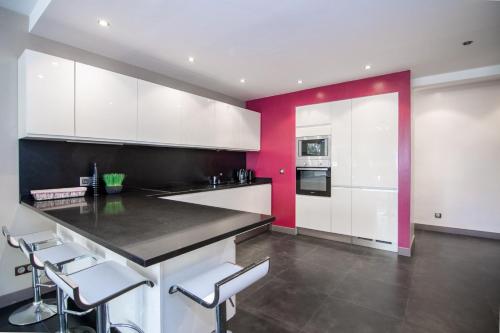 une cuisine avec des placards blancs et un mur aux accents rouges dans l'établissement Beau 3P proche hippodrome - Parking privé, à Cagnes-sur-Mer