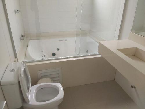 ein weißes Badezimmer mit Toilette und Badewanne in der Unterkunft Casa de Verão no Condomínio Porto Coronado in Xangri-lá