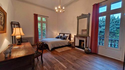 a bedroom with a bed and a table and a fireplace at Le Manoir de la Belle Endormie in Valréas