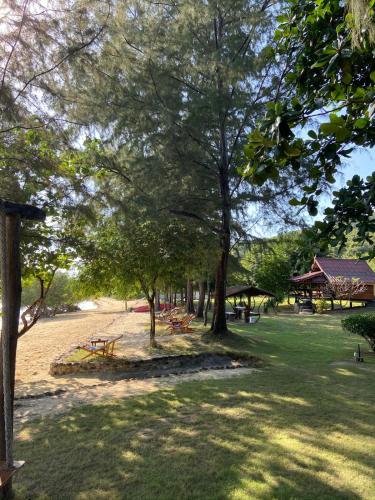 a park with picnic tables and trees in the grass at Angthong Beach Resort in Koh Phaluai