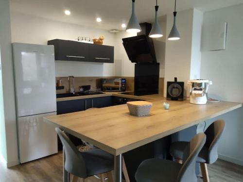 une cuisine avec un comptoir en bois et des chaises dans l'établissement Appartement deux chambres au pied de la dune, à Lacanau