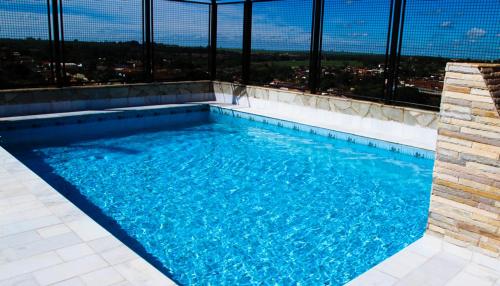 a swimming pool with a view of a city at Mabruk Barretos Apart Hotel in Barretos
