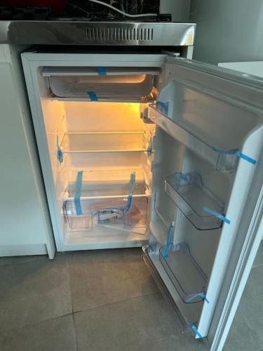 un réfrigérateur vide avec sa porte ouverte dans une cuisine dans l'établissement Parisien Duplex à Montreuil, à Montreuil