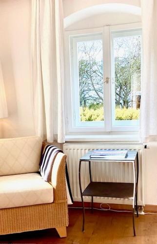 a living room with a table and a chair and a window at Hotel Fischerhaus in Starnberg
