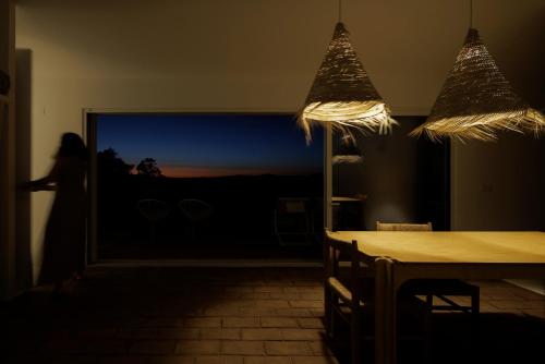 a woman walking into a room with a table and lights at Vagar do Pastor in Alandroal
