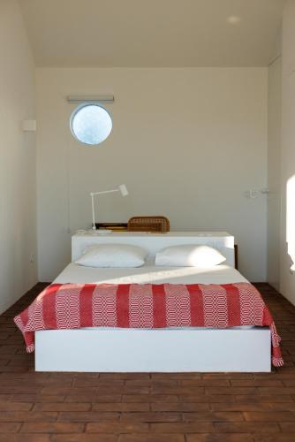 a bedroom with a bed with a red and white blanket at Vagar do Pastor in Alandroal