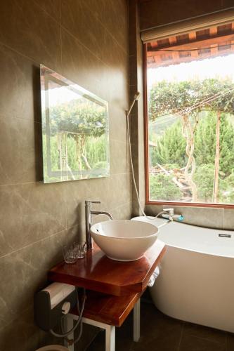 a bathroom with a sink and a tub and a window at Gỗ Home in Ðinh An (2)