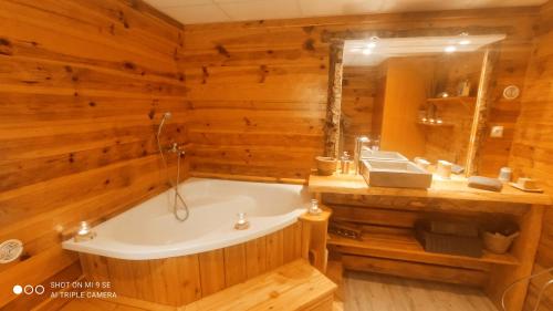 a wooden bathroom with a tub and a sink at L'appartement du chalet in Méolans