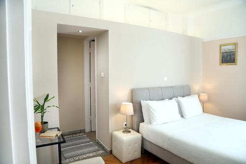 a white bedroom with a bed and a table at My Athens House in Athens