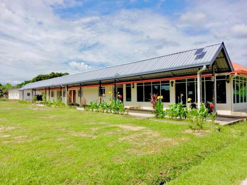 a large building with a field in front of it at Deluxe Room Mandahan Beach Garden in Kimanis