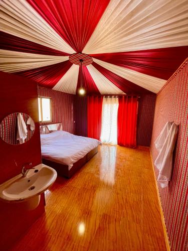 a bedroom with a bed with a red and white ceiling at Youssef camp Wadi Rum in Wadi Rum