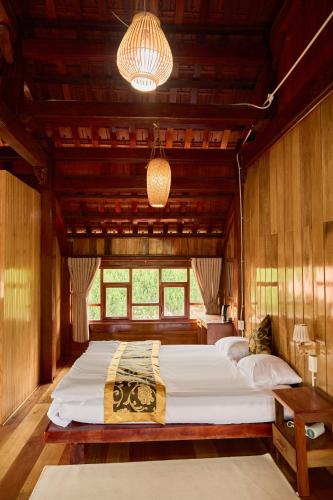 a large bed in a room with wooden walls at Gỗ Home in Ðinh An (2)