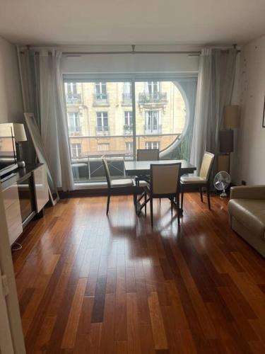 - un salon avec une table, des chaises et une grande fenêtre dans l'établissement Suite avec balcon vue Tour Eiffel, à Paris