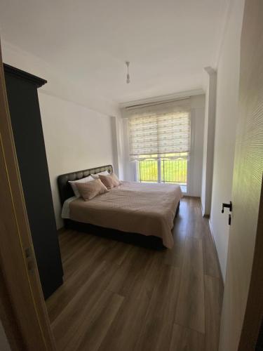 a bedroom with a bed and a large window at Dalaman Çınar Apart in Dalaman