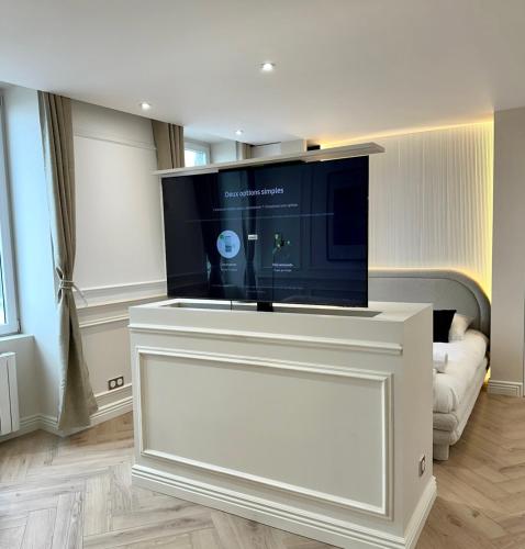 a large flat screen tv on a white stand in a living room at Les Rives de Saône - Balnéothérapie in Mâcon