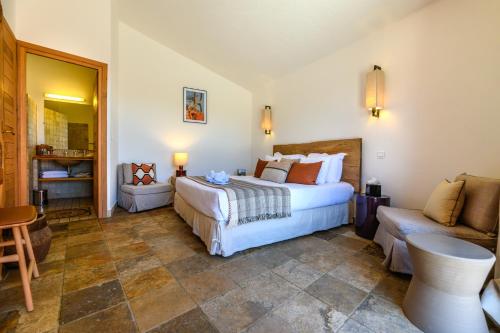 a bedroom with a bed and a chair and a couch at Les Bergeries De Palombaggia in Porto-Vecchio