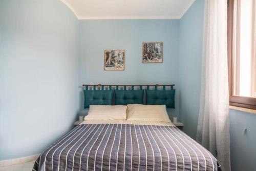 łóżko w niebieskiej sypialni z dwoma zdjęciami na ścianie w obiekcie Villa Silvana w mieście Mazara del Vallo