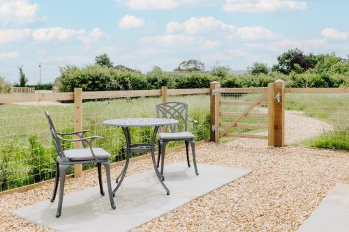 a patio with two chairs and a table and a fence at Luxury Glamping Pods with private Hot Tubs - Dog Friendly in Holsworthy