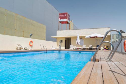 a large swimming pool in front of a hotel at Áticos Lux Sevilla Piscina Parking in Bormujos