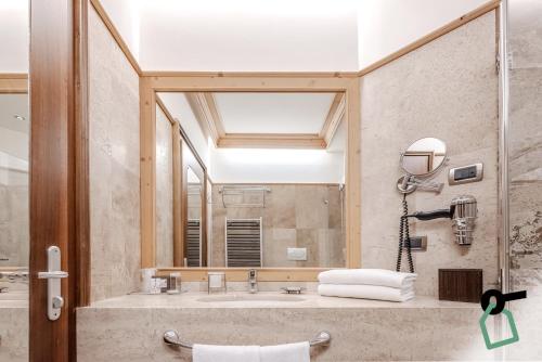 a bathroom with a sink and a large mirror at HOTIDAY Room Collection - Campiglio Pradalago in Madonna di Campiglio