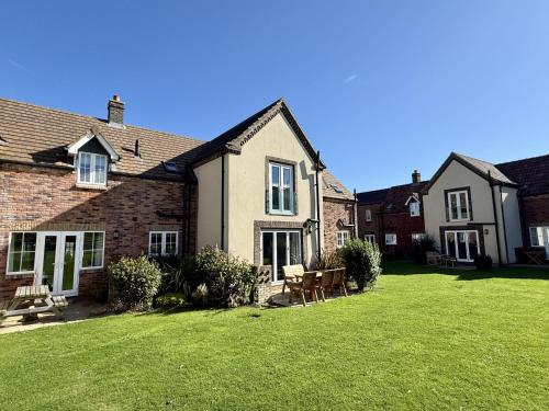 a house with a lawn in front of it at A Wave From It All - Part of the The Bay Filey Holiday Village with pool, gym and direct beach access, pub, restaurant, tennis and meadows walks in Filey