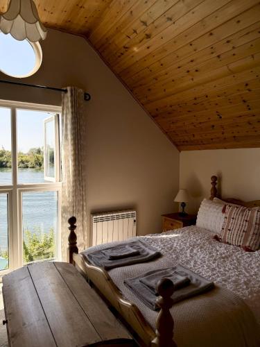 a bedroom with a large bed with a large window at Molly's Lodge - Cotswolds Lakeside Lodge in Gloucestershire