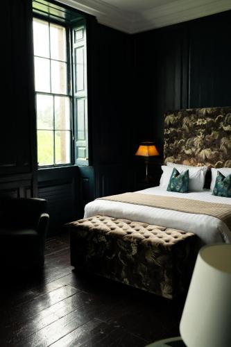 a bedroom with a large bed with a bench next to it at Bellinter House Hotel & Spa in Navan