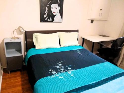 une chambre avec un lit avec une couverture bleue dans l'établissement Cozy basement apartment in the heart of Oakville, à Oakville