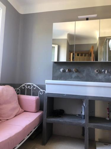 La salle de bains est pourvue d'un lavabo et d'un canapé rose. dans l'établissement Hope, villa à Aix en Provence, à Aix-en-Provence