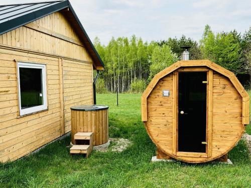 a wooden cabin with a door next to a trash can at Sielski domek w Starej Hucie in Stara Huta