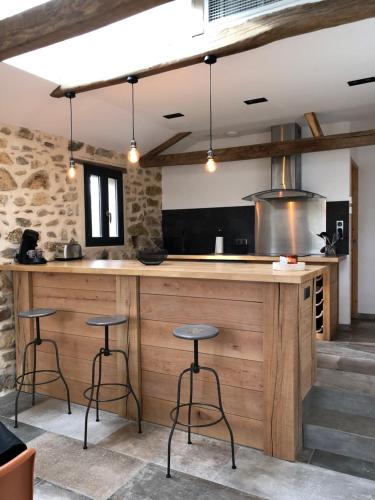 une cuisine avec un grand comptoir en bois avec des tabourets dans l'établissement Le gîte au bout du chemin, à Visker