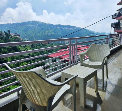two chairs and a table on top of a balcony at Luxury home with projector room near Kasauli in Dagshai