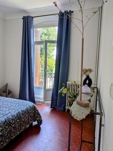 une chambre avec un lit et une fenêtre avec des rideaux bleus dans l'établissement Pagliano, à Manosque