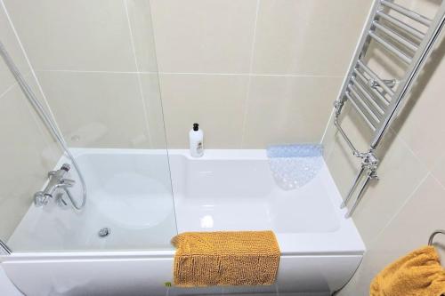 a white bath tub with a towel sitting on top of it at Cosy Central 2 En-suite Bedrooms Apartment in Hastings