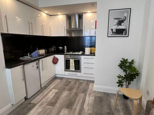 a kitchen with white cabinets and a wooden floor at Cosy Central 2 En-suite Bedrooms Apartment in Hastings