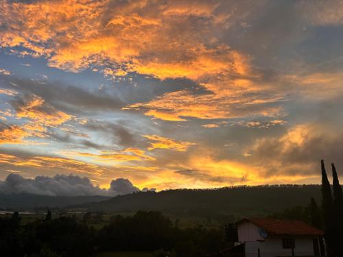 a cloudy sky at sunset with a house at Cabaña en Tapalpa Morada de Cervantes Bungalow Clavileño in Tapalpa