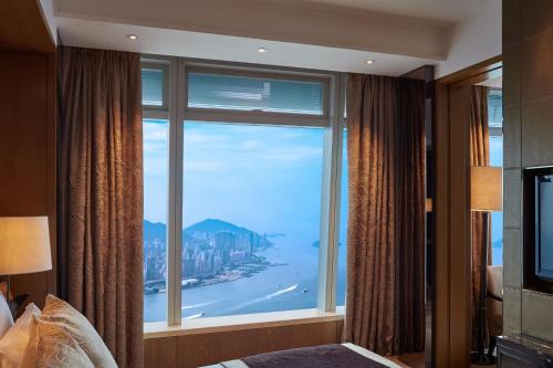 a bedroom with a large window with a view of the ocean at The Ritz-Carlton, Hong Kong in Hong Kong
