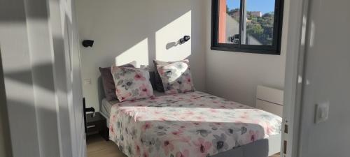 - une petite chambre dotée d'un lit avec un couvre-lit floral dans l'établissement T2 vue imprenable au calme, à Nice