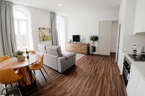 a living room with a table and a couch and a kitchen at Apartmento elegante in Figueira da Foz