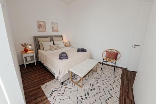 a bedroom with a white bed and a chair at Apartmento elegante in Figueira da Foz