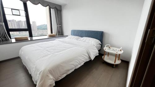 博罗Peicui Apartment的白色卧室配有一张带边桌的床