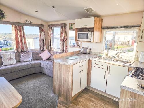 a caravan kitchen and living room with a couch at Summer Breeze in Perranzabuloe