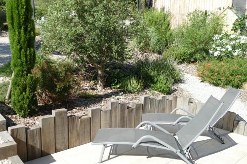 Deux chaises blanches et une clôture dans un jardin dans l'établissement Les Terrasses du Salagou - Superbe vue sur le lac, à Liausson