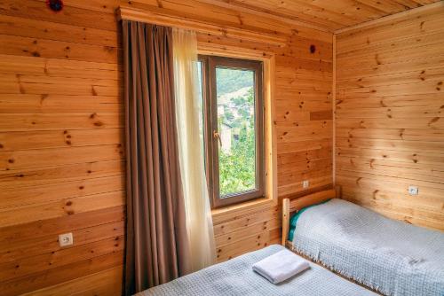 una camera da letto in una baita di tronchi con finestra di Ioane's Chalet a Mestia