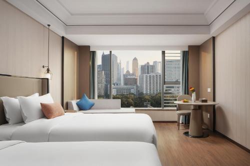 a hotel room with two beds and a large window at Mehood Lestie International Hotel Linhexi Guangzhou East Railway Station Branch - Free Shuttle Bus to Canton Fair Complex During Canton Fair Period & Free afternoon tea & Free midnight snack & Free VPN Internet Access in Guangzhou