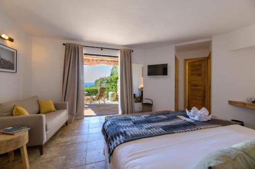 a bedroom with a bed and a living room with a couch at Les Bergeries De Palombaggia in Porto-Vecchio