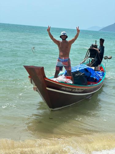 a man standing on a boat on the beach at Angthong Beach Resort in Koh Phaluai